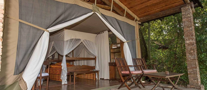 Luxury tented suite at Fig Tree Camp in the Maasai Mara, featuring a private verandah with canvas flaps open to the surrounding forest.