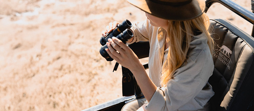 Guest spotting wildlife with binoculars on a luxury safari in South Luangwa National Park, Zambia