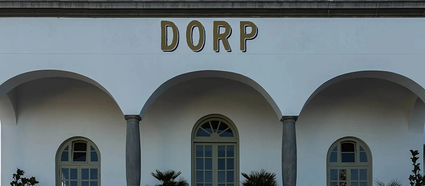 Close-up of Dorp Hotel’s grand arched entrance with gold-lettered signage and elegant architectural detailing.