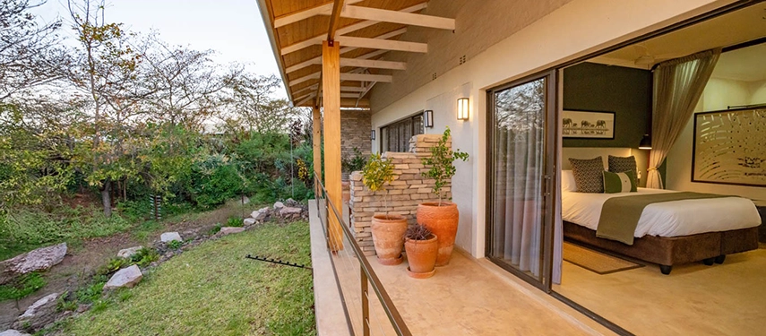 Private terrace with potted plants and garden views leading to a luxury suite at Insika Lodge, Victoria Falls.
