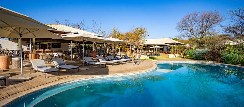Outdoor swimming pool surrounded by sun loungers and shaded deck at Insika Lodge, Victoria Falls.