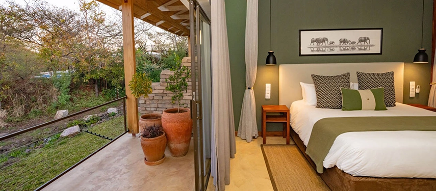 Garden-facing suite with potted plants and sliding doors opening onto a private terrace at Insika Lodge, Victoria Falls.