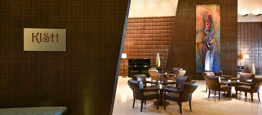 The refined interior of Kish Bar, featuring leather armchairs, textured walls, and contemporary artwork in an intimate lounge setting.