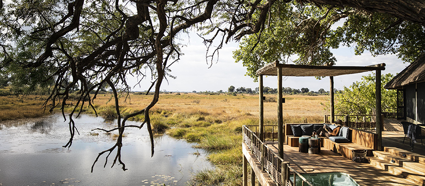 Guest relaxing on a private balcony overlooking a lagoon at King's Pool luxury safari Camp, Linyanti, Botswana