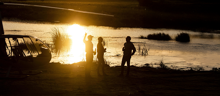 Guests pause for riverside sundowners in Linyanti, Botswana
