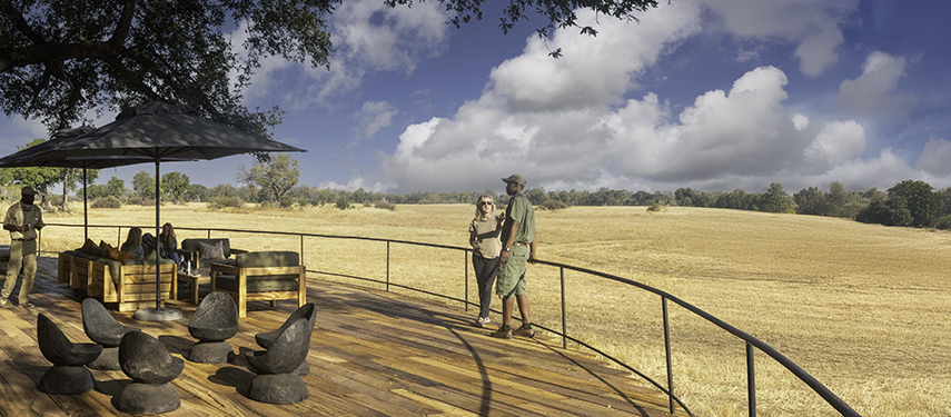 Elevated wooden deck at Kiri Camp with guests enjoying panoramic views of golden floodplains.