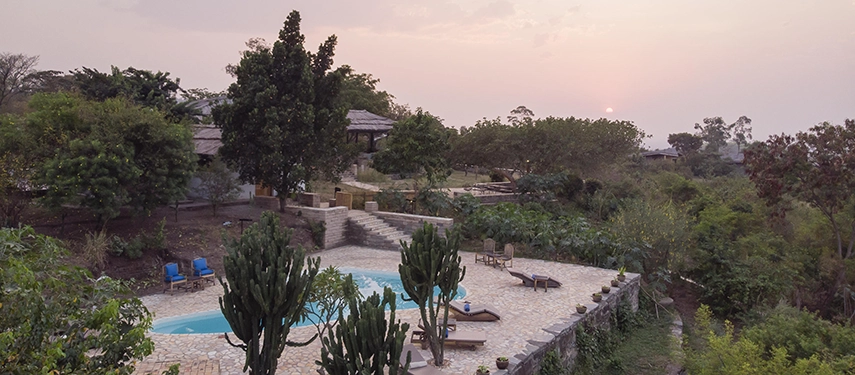 The swimming pool at Kyambura Gorge Lodge set within stone terraces and gardens, offering a tranquil place to unwind after wildlife experiences.