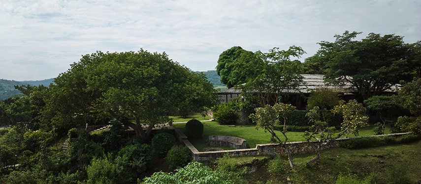 The landscaped gardens of Kyambura Gorge Lodge framed by mature trees and sweeping views across the forested gorge.