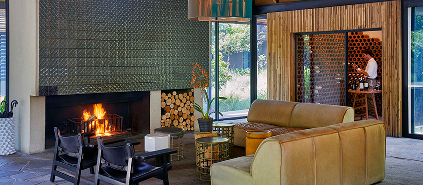 Stylish lounge and bar area at Lion Sands River Lodge with a glowing fireplace and modern African design.