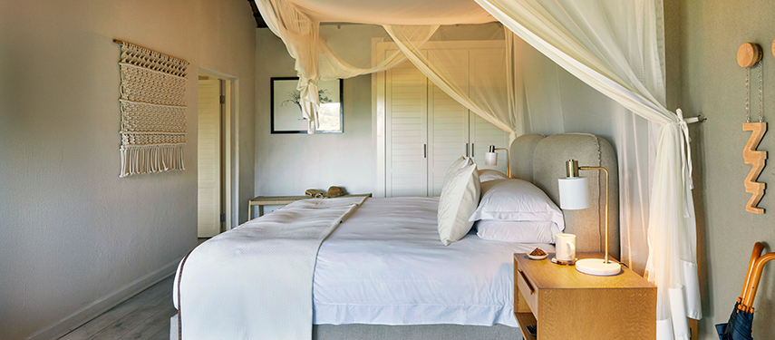 Light-filled luxury room with white linen, mosquito netting, and minimalist decor.