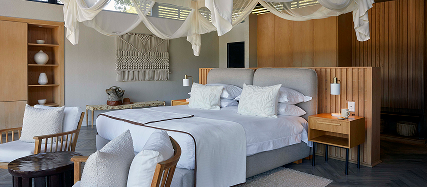 Spacious river suite bedroom with soft textiles, neutral palette, and canopy-draped bed.