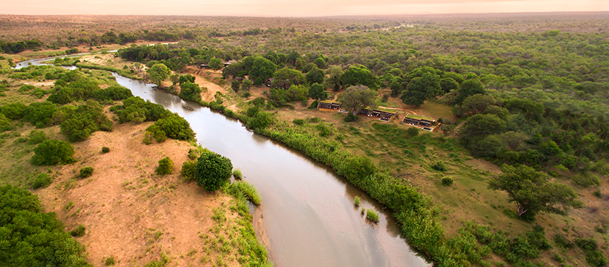 Expansive aerial image showing Lion Sands River Lodge nestled between the river and surrounding forest.