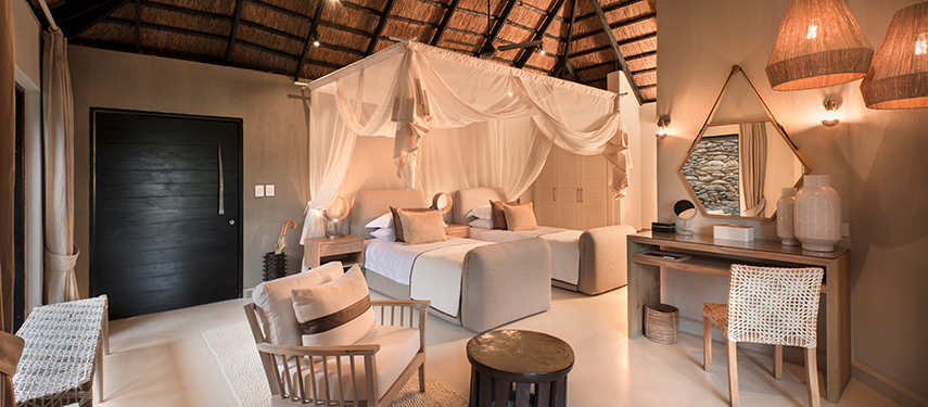 Elegant twin-bedded luxury suite with canopy netting and earthy, neutral tones.