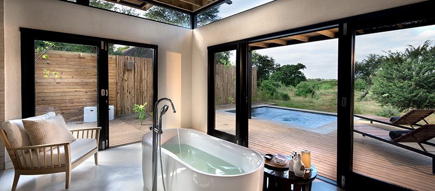 Freestanding bathtub in a bright en suite bathroom, opening onto a private deck with plunge pool.