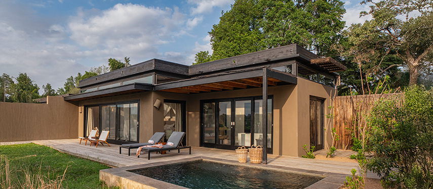Exterior of a modern river suite with private plunge pool and sun loungers under a blue sky.