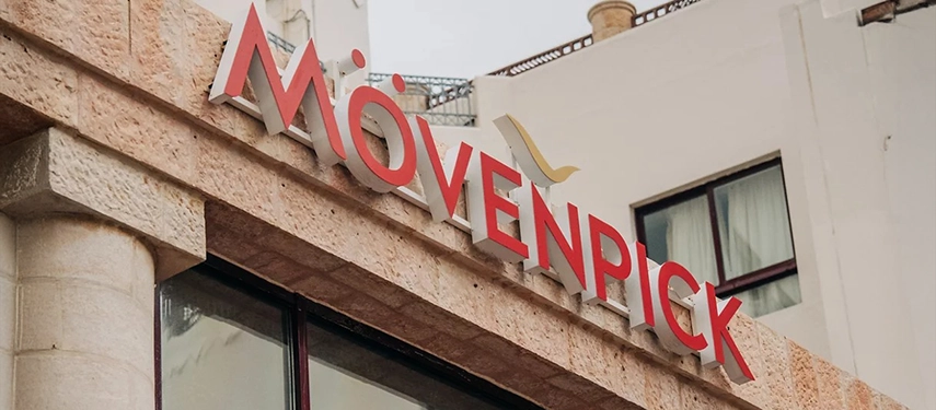 The Mövenpick Hotel Petra exterior signage is mounted against warm stone walls, marking the hotel’s prime location near Petra’s entrance.