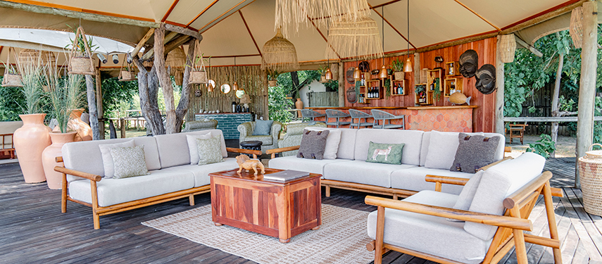 An inviting open-air lounge at Dulini Anabezi with plush seating, a wooden bar, and forest views.