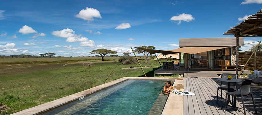 Woman lounging in a pool as she gazes across the Masai Mare from Namiri Plains Retreat