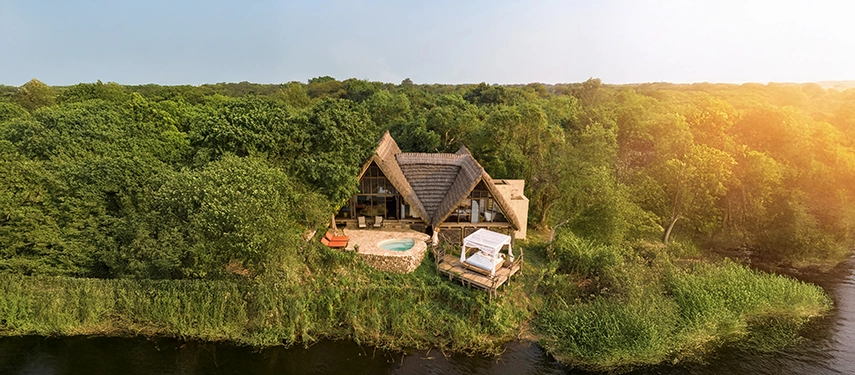 Aerial view of the lodge tucked into lush greenery beside the Victoria Nile, emphasising its privacy and intimate connection to the landscape.