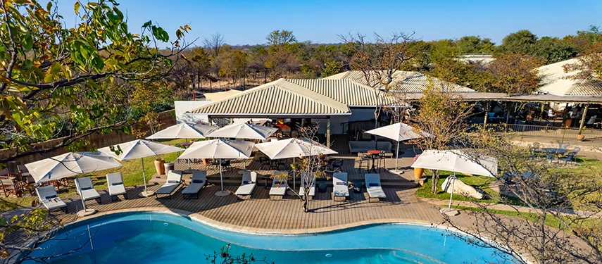Aerial view of the pool deck surrounded by umbrellas and sun loungers at Insika Lodge, Victoria Falls.