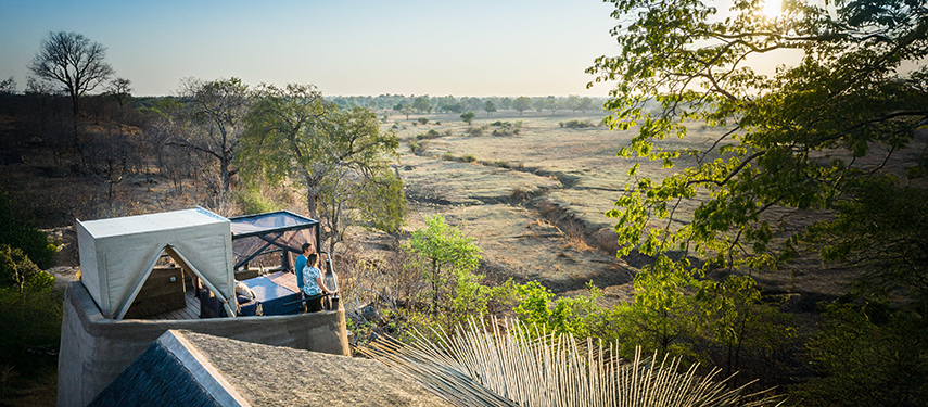 Couple in starbed overlooking grassy plains at Puku Ridge, Zambia