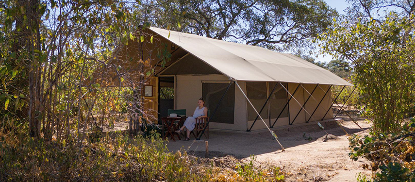 Guest sitting outside a tented suite at Mhara River Camp, Mana Pools, Zimbabwe