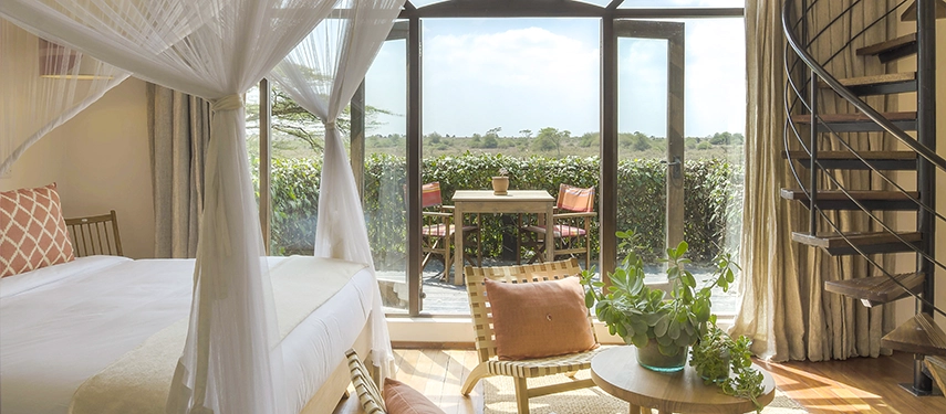 Charming double-storey suite with four-poster bed, spiral staircase, and sweeping views from the private upper-level terrace.