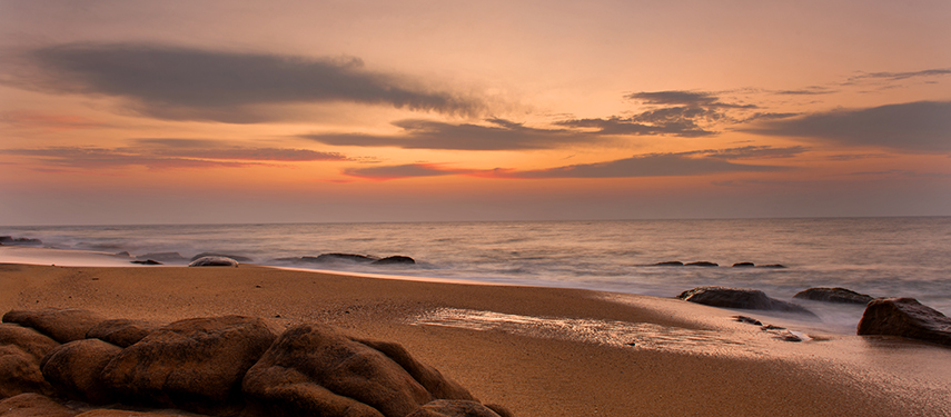 A time-lapse sunset image of the Sri Lankan coast with waves crashing on rocks
