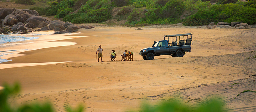 Tourist couple enjoy a beach picnic next to a four-wheel drive in Sri Lanka