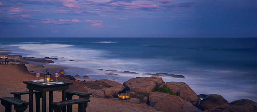 A time-lapse sunset image of the Sri Lankan coast with waves crashing on rocks