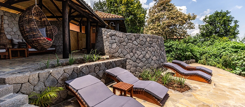Sun loungers line the stone terrace at Virunga Lodge, overlooking forested slopes and providing a peaceful space to unwind after gorilla trekking.