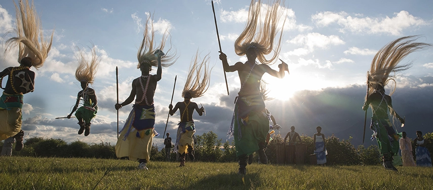 Traditional Intore dancers perform on open grassland near Virunga Lodge, their movement and dress celebrating Rwanda’s living cultural heritage.