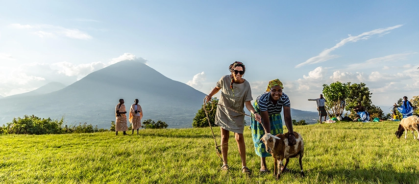 Guests enjoy a gentle walk through rural farmland near Virunga Lodge, with Mount Muhabura rising in the background and local life unfolding across the hills.