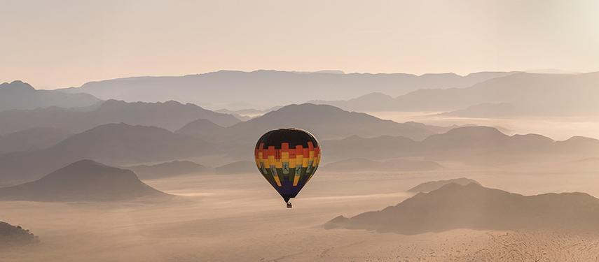 Hot-air balloon drifts across the Namibian Sossusvlei desert at sunrise