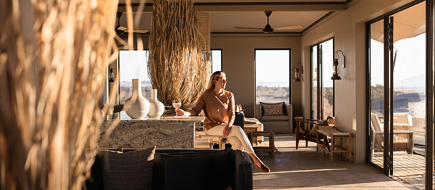 Guest at Kulala Desert Lodge looks across the Namibian desert from her luxury suite