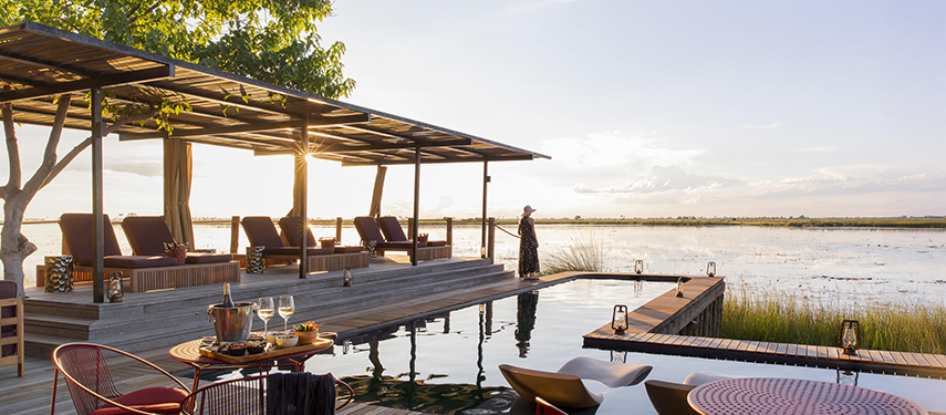 Guest stands next to a swimming pool at a luxury safari camp in Linyanti Reserve, Botswana