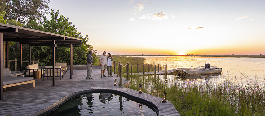 Couple standing next to a plunge pool on the banks of the Linyanti River at sunset