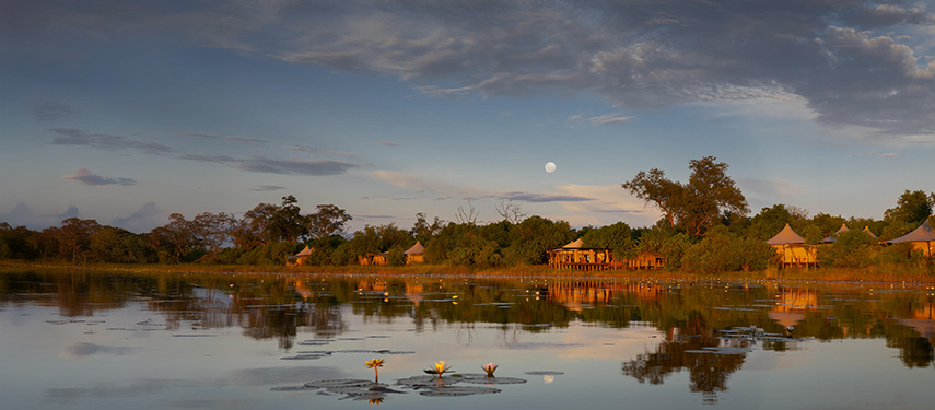 Little DumaTau tented safari camp on a riverbank at sunset