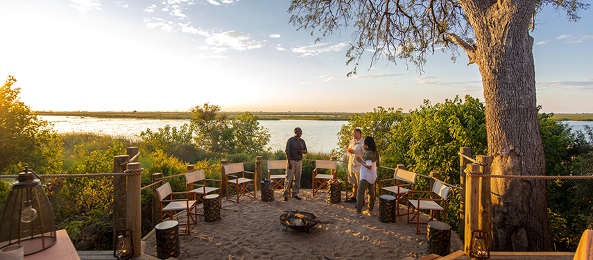 Guests talk to a guide on the deck of Little DumaTau tented safari camp