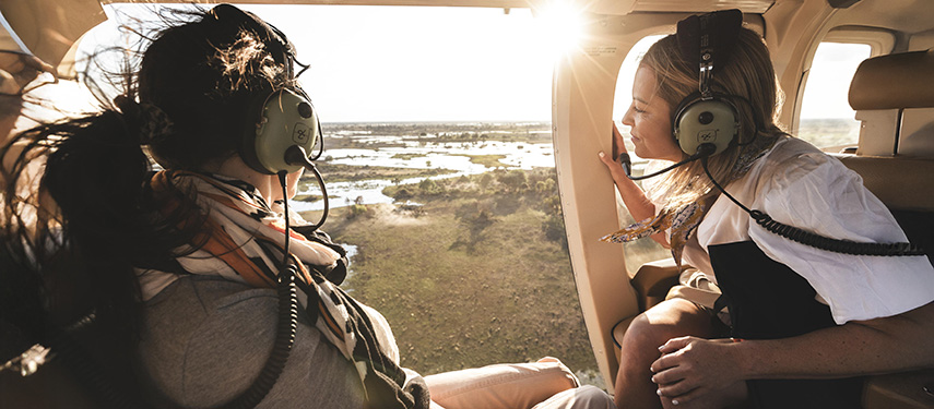 Two female guests view the Okavango Delta from above on a helicopter flight