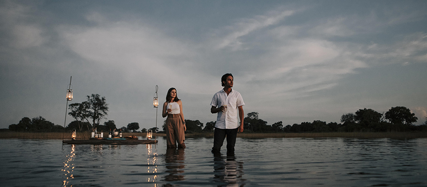 Couple enjoys a sunset picnic in the waters of thew Okavango Delta