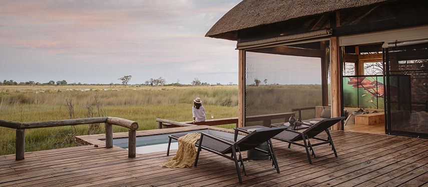 Guest looks out over the grassy plains from Vumbura Plains safari lodge in Botswana's Okavango Delta