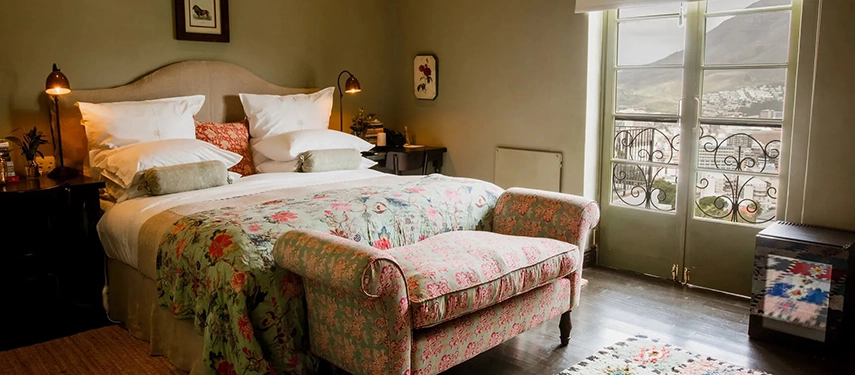 Hillside view of Dorp Hotel’s white buildings nestled among trees, overlooking Cape Town’s cityscape below.