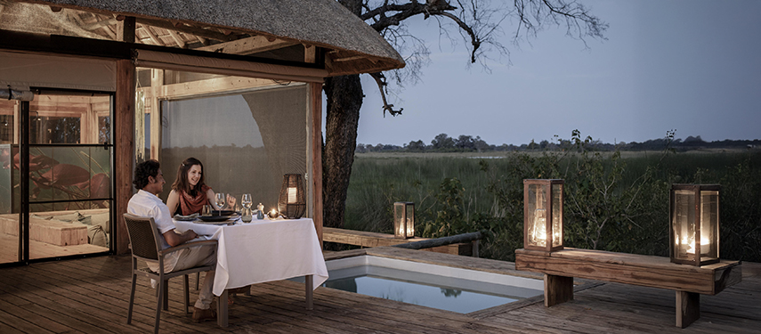 Couple enjoy a sunset dinner next to a private plunge pool at their suite at Vumbura Plains safari lodge in Botswana's Okavango Delta