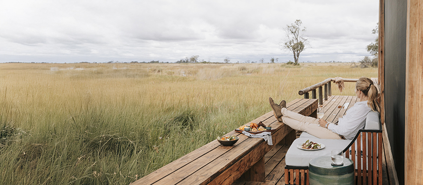 Guest looks out over the grassy plains from Vumbura Plains safari lodge in Botswana's Okavango Delta