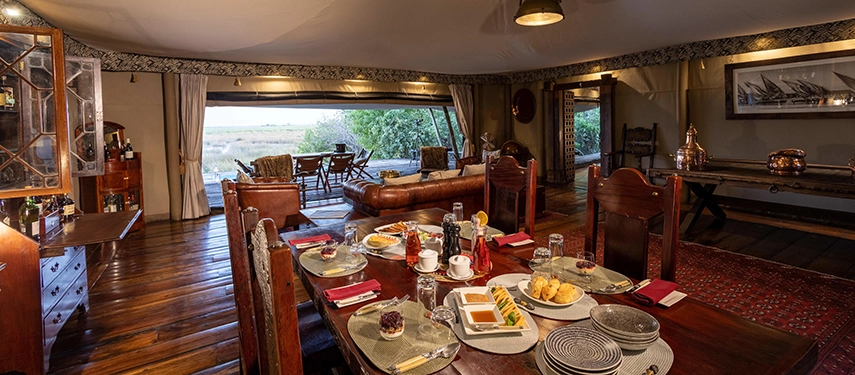 In-suite dining table set inside the Zarafa Dhow Suite in the Selinda Reserve, with views opening out across the floodplains beyond the tented walls.