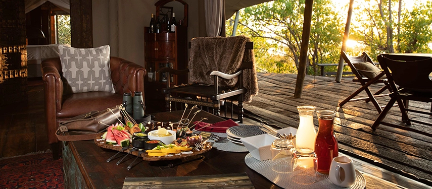 Private in-suite dining at sunset in the Zarafa Dhow Suite in the Selinda Reserve, with relaxed seating and views across the surrounding wilderness.