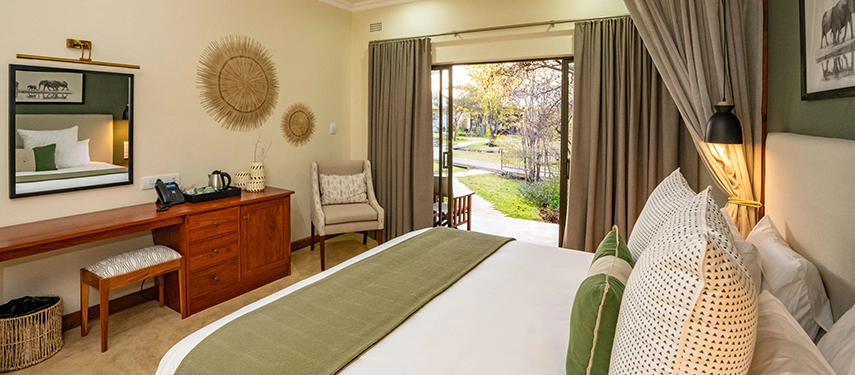 Elegant bedroom with green accents, writing desk and sliding doors opening to the garden at Insika Lodge, Victoria Falls.