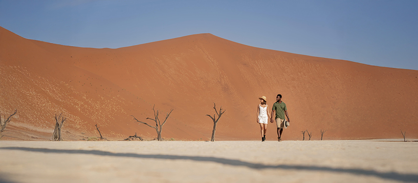 Couple walks through the stunning landscape of Deadvlei, surrounded by sand dunes.