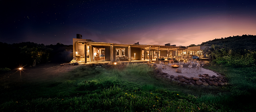 Gwegwe Beach Lodge’s main building lit up under a starry night sky.